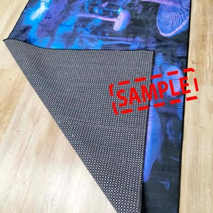 Puede incluir: Una alfombra negra y azul con un dise&ntilde;o de setas psicod&eacute;licas. La alfombra tiene un respaldo antideslizante y est&aacute; etiquetada como "SAMPLE".