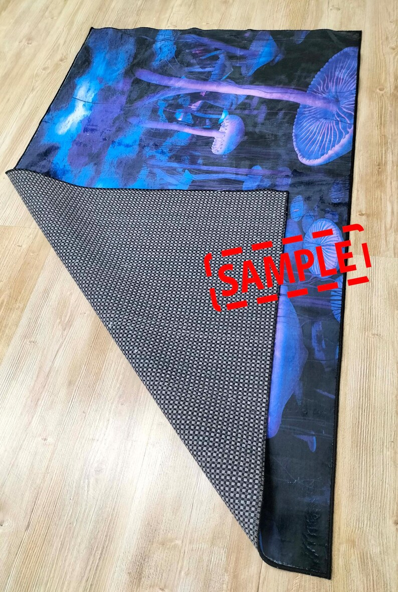 Puede incluir: Una alfombra negra y azul con un dise&ntilde;o de setas psicod&eacute;licas. La alfombra tiene un respaldo antideslizante y est&aacute; etiquetada como "SAMPLE".