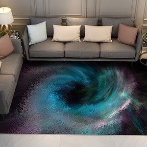 May include: A dark blue, green, and purple abstract area rug with a swirling pattern. The rug is in front of a gray sofa with pillows.