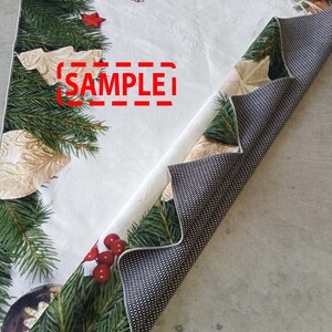 May include: A Christmas-themed table runner with a white background and festive decorations. The runner features green pine branches, red berries, and gold ornaments. The text "SAMPLE" is visible on the runner.