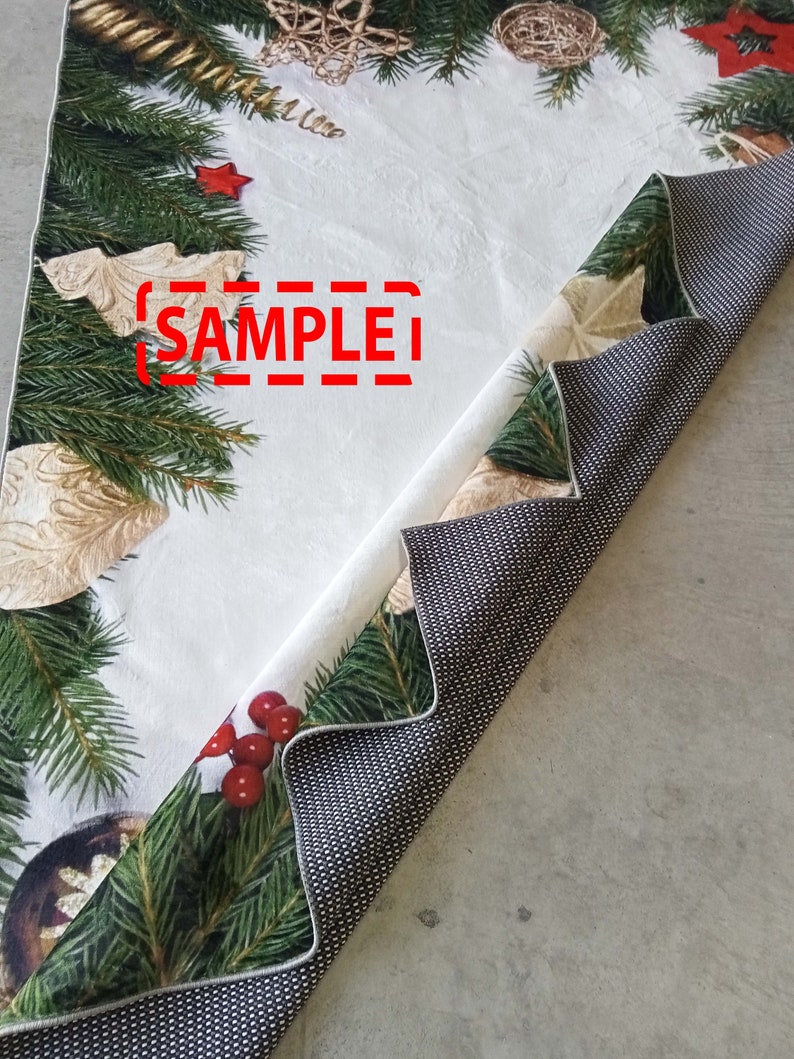 May include: A Christmas-themed table runner with a white background and festive decorations. The runner features green pine branches, red berries, and gold ornaments. The text "SAMPLE" is visible on the runner.