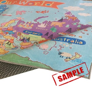 May include: A colorful children's play mat featuring a world map design. The map includes continents, oceans, and country names in various colors. The text "Our World" is at the top. The word "SAMPLE" is stamped in red.