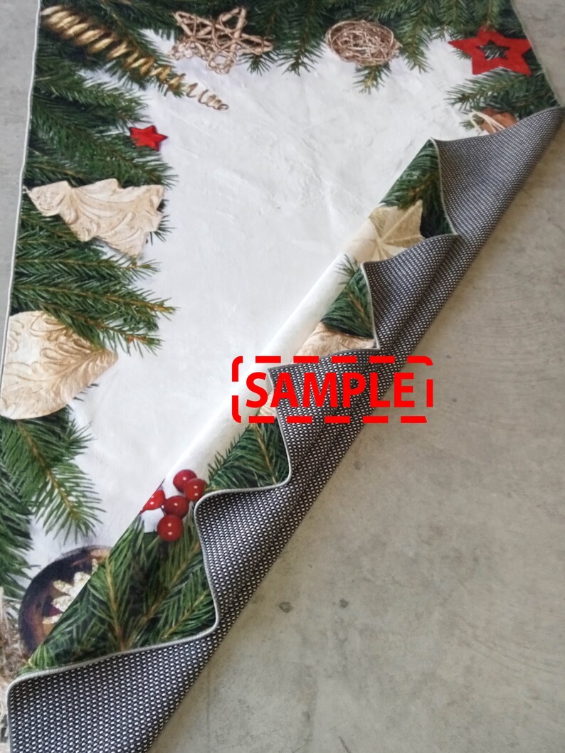 May include: A Christmas-themed table runner with a white background and festive green fir branches, red berries, and gold ornaments. The reverse side features a black and white dotted pattern. The word "SAMPLE" is visible.