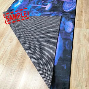 Puede incluir: Una alfombra azul y negra con un dise&ntilde;o de setas psicod&eacute;licas. La alfombra tiene un respaldo antideslizante.