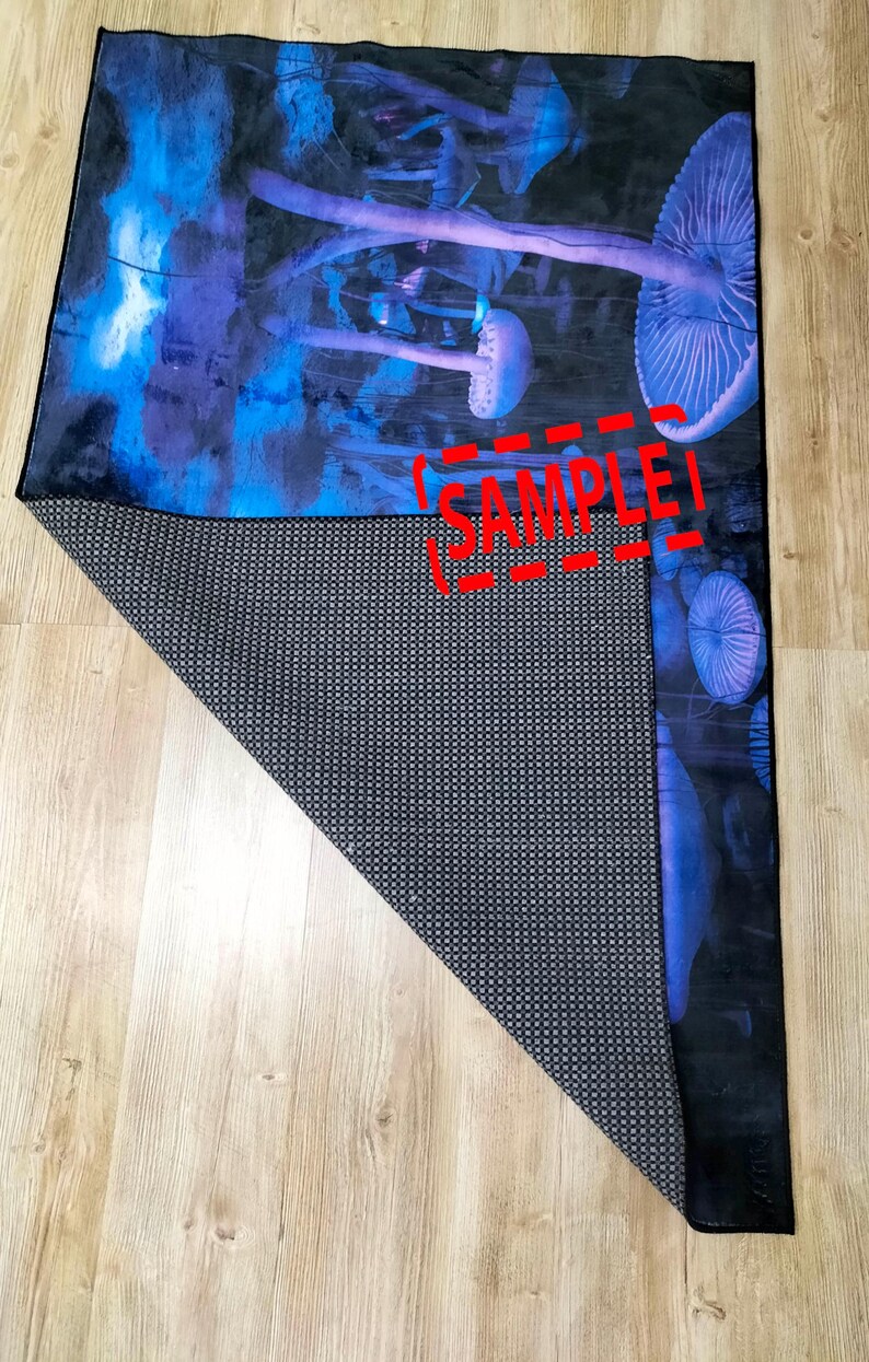 Puede incluir: Una alfombra de ba&ntilde;o azul y morada con un dise&ntilde;o de hongos. La alfombra tiene un respaldo antideslizante negro. La alfombra est&aacute; doblada por la mitad y la parte posterior es visible. La alfombra tiene la palabra "SAMPLE" impresa en ella.