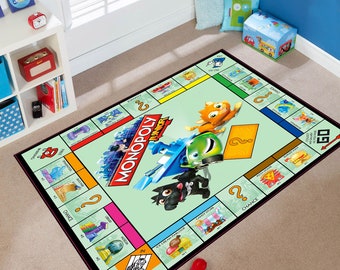 May include: A green and black Monopoly Junior game board rug with a cartoon car, dog, and cat. The rug features the words "Monopoly Junior" and "Go!" in black text.