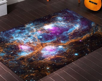 May include: A rectangular rug with a galaxy print featuring swirling blue, purple, and orange nebulae against a dark blue background with scattered white stars.
