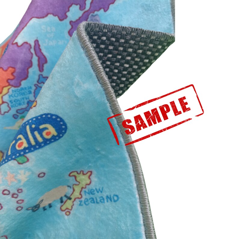 May include: A section of a light blue map-themed rug with a world map design. The rug has a gray border and a non-slip backing. The word "SAMPLE" is stamped in red on the rug.
