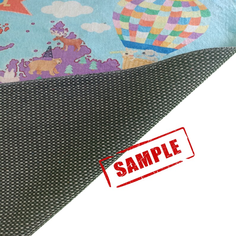 May include: A colorful children's play mat featuring a whimsical design with a hot air balloon, animals, and a map. The mat has a light blue background and a dark gray, textured underside. The word "SAMPLE" is stamped on the corner.