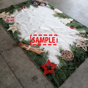 May include: A rectangular Christmas-themed table runner with a white center and a border of green pine needles. The border is decorated with red stars, gold ornaments, and cinnamon sticks. The word "SAMPLE" is printed in red.