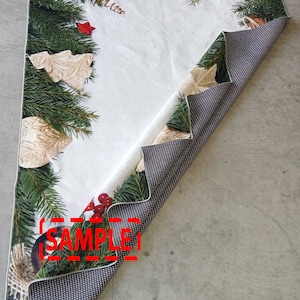 May include: A Christmas-themed table runner with a white center and a border of green pine branches, red stars, and gold ornaments. The reverse side is a dark gray with a dotted pattern. The word "SAMPLE" is visible.