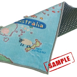 May include: A light blue children's rug featuring a map of Australia and New Zealand with cartoon illustrations of a sheep and other elements. The word "Australia" is in a blue bubble. The rug has a gray border and a non-slip backing.