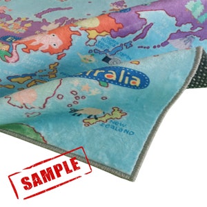 May include: A colorful rug featuring a world map design with continents and oceans in shades of blue, orange, purple, and green. The rug has a soft, plush texture and a gray border. The word "Australia" is visible on the rug.