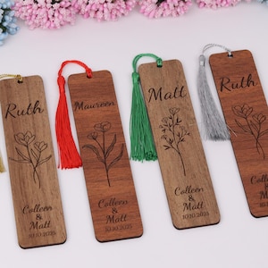 May include: Wooden bookmarks with engraved floral designs and names. Each bookmark has a tassel in a different color: gold, red, green, and silver. The names "Ruth", "Maureen", and "Matt" are engraved on the bookmarks, along with "Colleen & Matt 10.10.2025".
