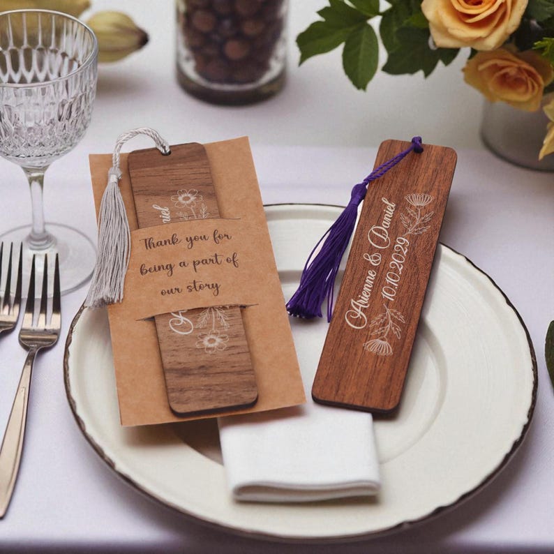May include: Wooden bookmarks with floral designs and tassels. One bookmark is paired with a card that reads "Thank you for being a part of our story." The other bookmark has the names "Aienne & Daniel" and the date "10.10.2029."