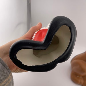 Puede incluir: Una figura de cer&aacute;mica de Pap&aacute; Noel con un gorro rojo y barba blanca. La figura lleva un saco y tiene una base negra.