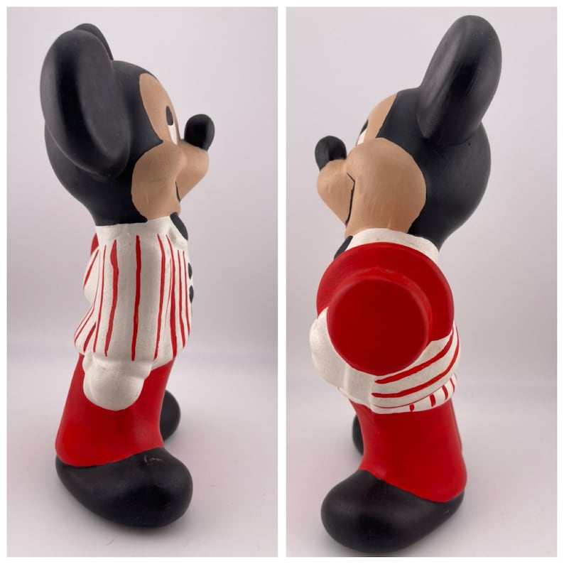 Puede incluir: Una figurita de cer&aacute;mica de Mickey Mouse con una camisa a rayas rojas y blancas y pantalones rojos. Est&aacute; sosteniendo un sombrero rojo en su mano derecha.