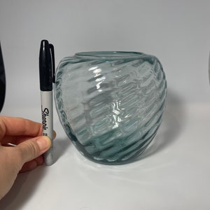May include: A clear glass vase with a textured, wavy design. The vase is approximately 5 inches tall.