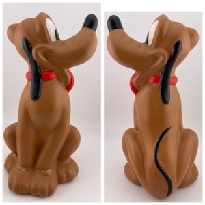 Puede incluir: Una figurita de cer&aacute;mica marr&oacute;n de Pluto, el perro de Disney. Pluto est&aacute; sentado con la cola enroscada detr&aacute;s de &eacute;l y lleva un collar rojo.
