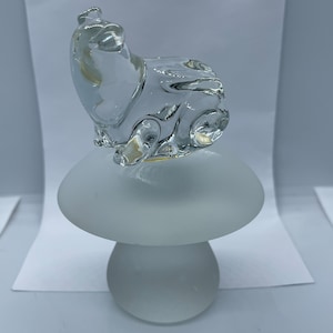 May include: A clear glass animal figurine of a bear sitting on a frosted white glass mushroom base.