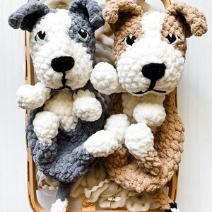 May include: Two crocheted stuffed dog toys in a wooden basket. One dog is gray and white, the other is brown and white.