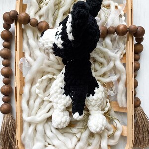 May include: A black and white crocheted dog toy in a wooden basket with white yarn and brown wooden beads.