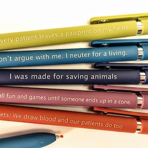 Può includere: Una collezione di penne colorate con citazioni umoristiche a tema veterinario in lettere bianche. Le penne sono in tonalità di verde, blu, viola e rosso. Le citazioni includono frasi sulla cura degli animali e il lavoro veterinario.