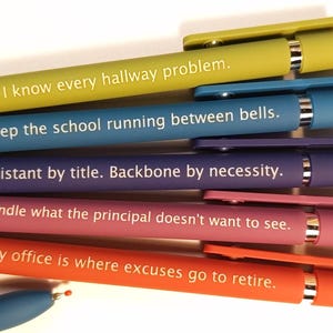 May include: A collection of colorful pens in yellow, blue, purple, pink, and orange. Each pen has a different white text inscription. The pens are a school-themed product.