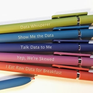 May include: A set of six retractable ballpoint pens in lime green, blue, dark blue, pink, orange, and light blue. Each pen features white text: Data Whisperer, Show Me the Data, Talk Data to Me, Yep, We're Skewed, and I Eat Raw Data for Breakfast.