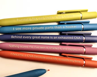 Op de afbeelding: Een verzameling kleurrijke pennen met humoristische zinnen erop gedrukt. De pennen zijn in tinten groen, blauw, paars, roze en rood. De tekst bevat zinnen als "Running for call bells is my cardio" en "I see more private parts".