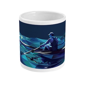 May include: White ceramic mug featuring a geometric illustration of a rower in a boat on a teal and blue sea. The design wraps around the mug, creating a dynamic and artistic visual. The mug has a white interior and a simple, clean design.
