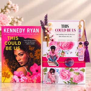 May include: A book titled This Could Be Us by Kennedy Ryan next to a gift set featuring a card with the same title, a gold pen, dried lavender, a beaded bookmark with a purple tassel, and a floral-patterned box with stickers.