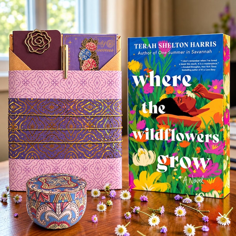 A book titled Where the Wildflowers Grow by Terah Shelton Harris next to a purple patterned gift box containing a notebook, a gold metal rose paperclip, and a floral bookmark, with a small round patterned tin in the foreground.