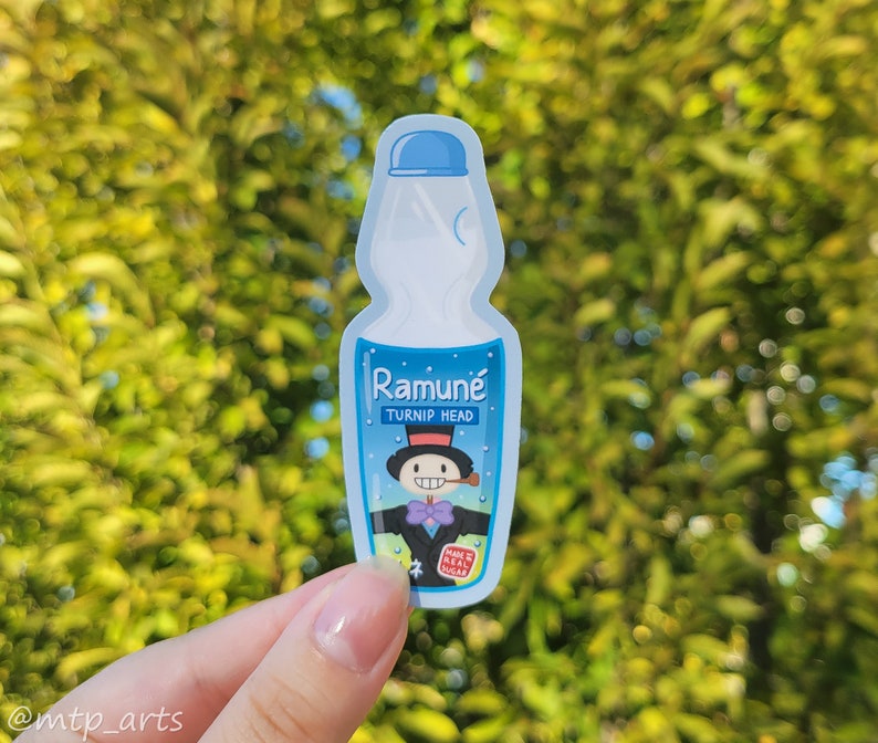 Peut inclure: Un autocollant bleu et blanc repr&eacute;sentant une bouteille de Ramune avec un personnage de dessin anim&eacute; sur l'&eacute;tiquette. L'&eacute;tiquette indique "Ramune Turnip Head" et "Made with Real Sugar".