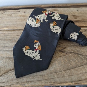 May include: A black silk tie with a repeating pattern of Dalmatian puppies. The puppies are white with black spots and are in various poses.