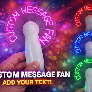 May include: A white handheld fan with a clear, circular LED display. The display shows the text "CUSTOM MESSAGE FAN" in bright, colorful lights. The image also shows the text "ADD YOUR TEXT!" and several fans with different colored lights.