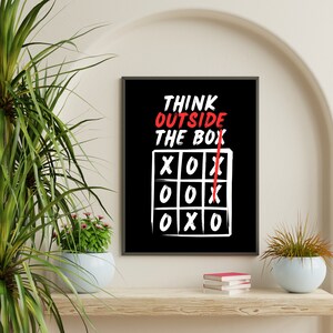 May include: Black and white motivational poster with the text "Think outside the box" and a red line drawn through the word "box". The box is a tic-tac-toe game board with X's and O's.