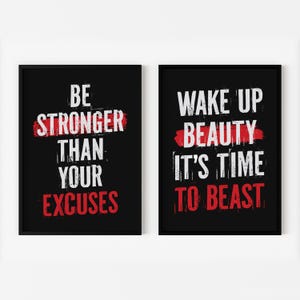 May include: Two black framed motivational posters with white text on a black background. The left poster says "Be Stronger Than Your Excuses" with a red line through the word "Stronger". The right poster says "Wake Up Beauty It's Time To Beast" with a red line through the word "Beauty".