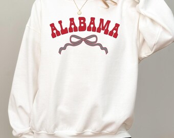 May include: White sweatshirt with a red "ALABAMA" graphic and a gray bow.