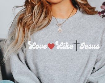 May include: Gray sweatshirt with the text "Love Like Jesus" in white with a red heart and a black cross.
