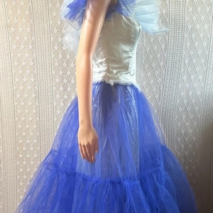 May include: A vintage-style formal gown. The bodice is a light satin, and the skirt is a layered, voluminous blue tulle. The gown features a ruffled collar and shoulder detail in white and blue. The dress is displayed on a mannequin.