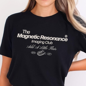 May include: Black t-shirt with white text that reads "The Magnetic Resonance Imaging Club Add A Little Flair." The shirt also has a graphic of a horseshoe and the text "ESTD 1977."