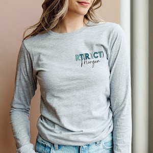 May include: Gray long-sleeve shirt with a teal and blue graphic that says "RTR(XCT)" and "Morgan" in black text.