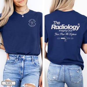 May include: A navy blue t-shirt with a white graphic on the front that says "Radiologic Technologist" and a white graphic on the back that says "The Radiology Imaging Club You Pose We Expose" with a stylized image of an x-ray machine.