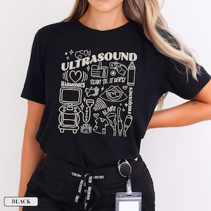 May include: Black t-shirt with a white graphic design of ultrasound equipment and the text "ULTRASOUND", "HARMONICS", "SCAN TIL IT HERTZ", "FOCUS", "ALARA", and "FREQUENCY".