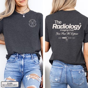 May include: A dark heather grey t-shirt with a white graphic on the front that says "Radiologic Technologist" and a white graphic on the back that says "The Radiology Imaging Club You Pose We Expose".