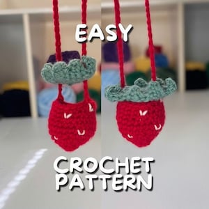 May include: Two crocheted strawberry-shaped bags with green leaves hanging from red strings. The text "EASY CROCHET PATTERN" is below the bags.