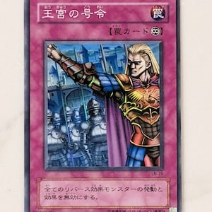Op de afbeelding: Een Japanse trading card game kaart met een roze achtergrond en een afbeelding van een man in harnas met een zwaard. De kaart heeft de titel "Koninklijk Decreet" en de tekst "Valkaart" erop. De kaart is van het trading card game "Yu-Gi-Oh!"