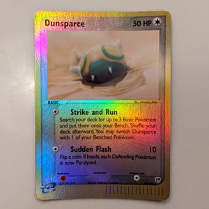 May include: A Dunsparce Pokemon card from the Expedition set. The card is holographic and features a green and yellow Dunsparce illustration. The card text reads "Strike and Run" and "Sudden Flash".
