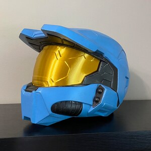 May include: A blue and gold plastic helmet with a visor. The helmet has a textured surface and a black trim around the visor.
